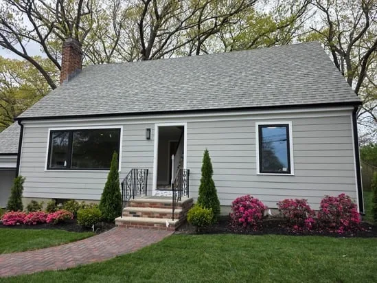 iew of a newly completed residential exterior painting job showcasing the modern gray exterior and black window frames.
